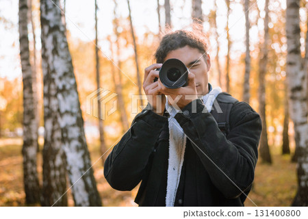 Portrait of a young male photographer shooting landscapes in the autumn forest 131400800