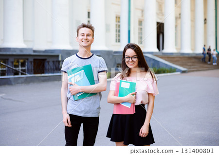 Two happy students in front of university with books and exercise books 131400801