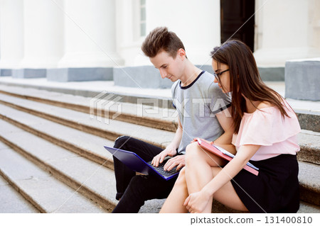 Students sitting on the stairs of old university working on project, communicate, search for information in the Internet 131400810