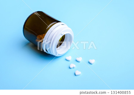 Some white pills in the shape of heart fell down from glass bottle Some white pills in the shape of heart fell down from glass bottle 131400855