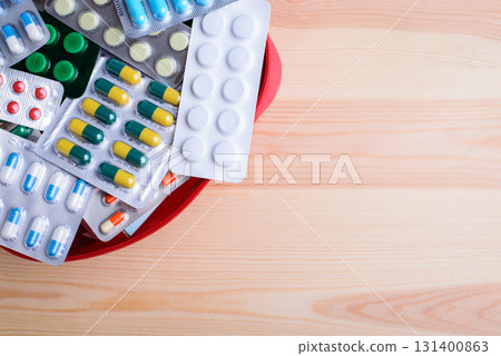 Red bag with many different pills against wooden table with place for inscription. Concept of pills, health care, medicine Red bag with many different pills against wooden table with place for inscription. Concept of pills, health care, medicine 131400863