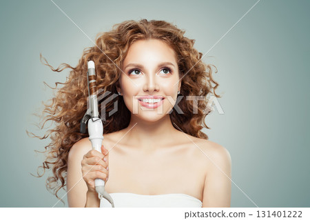 Cute woman with long wavy hairstyle using hair curling tongs iron,. Hairdresser equipment tools Cute woman with long wavy hairstyle using hair curling tongs iron,. Hairdresser equipment tools 131401222