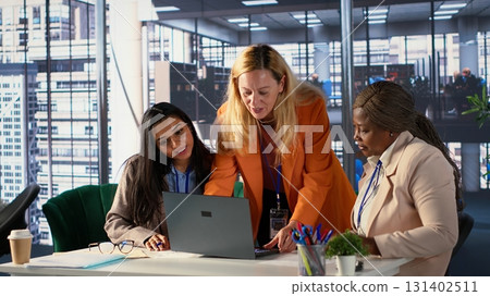 Diverse team of women collaborate in a problem solving meeting, promoting gender equality and social development in business industry. Managers demonstrating teamwork and progression. Camera A. 131402511