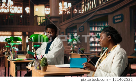 African american med school enjoying lecture from specialty books at the library, doing her medical research and learning about healthcare methods. Woman working hard for her career. Camera A. 131402525