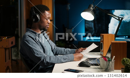 Investor contacting his accountant at home desk to go over current budget balance, boosting earnings via foreign investments. Man reviewing financial assets with consultant. Camera B. Investor contacting his accountant at home desk to go over current budget balance, boosting earnings via foreign investments. Man reviewing financial assets with consultant. Camera B. 131402614
