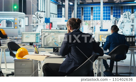 Photovoltaics factory manager taking notes after visualizing solar cells designs with 3D software tools. Solar panels plant technician draws schematics after doing computer simulations in CAD program Photovoltaics factory manager taking notes after visualizing solar cells designs with 3D software tools. Solar panels plant technician draws schematics after doing computer simulations in CAD program 131402636