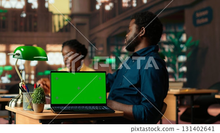 Team of students working on a class assignment next to copy space screen, consulting the educational database with books. African american university pupils prepare for exams. Camera B. Team of students working on a class assignment next to copy space screen, consulting the educational database with books. African american university pupils prepare for exams. Camera B. 131402641