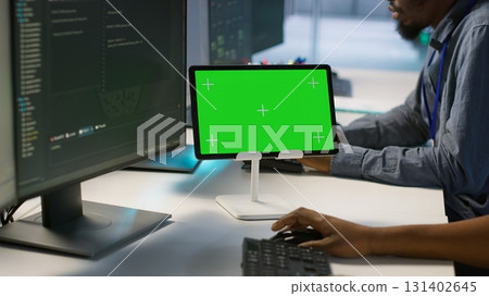 Team of programmer using green screen tablet, working in server farm to optimize it for data processing requirements. Teamworking colleagues coding on chroma key device in data center, camera A Team of programmer using green screen tablet, working in server farm to optimize it for data processing requirements. Teamworking colleagues coding on chroma key device in data center, camera A 131402645