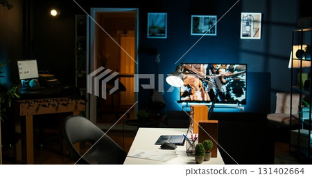 Urban apartment with a stylish home office setup with a wooden desk, house plants and a TV creating a cozy modern interior design. Spacious, creative and perfect for a homey lifestyle. 131402664