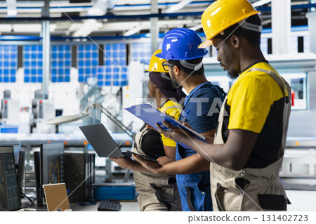 African american workers checking up on manufacturing equipment in solar panel factory, reading documentation files. Team of engineers in industrial facility inspecting production process. African american workers checking up on manufacturing equipment in solar panel factory, reading documentation files. Team of engineers in industrial facility inspecting production process. 131402723