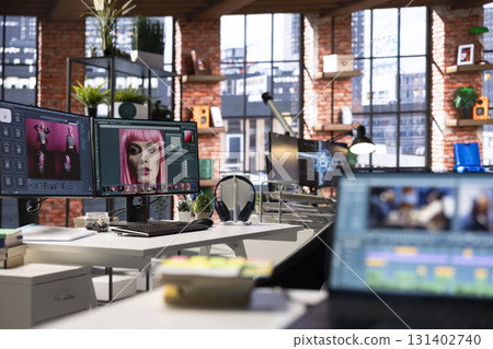 Empty graphic design studio with photo editing setup and AI chat software. Monitors display digital retouching software, color correction and enhancement tools for image processing. 131402740