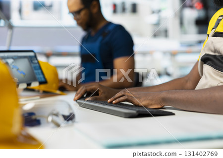 Solar power engineer updates design models in eco friendly factory with a focus on research and innovation. Male technician supports sustainable industrial growth using digital systems. 131402769