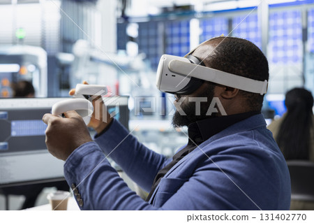Photovoltaics factory engineer designing on CAD software with VR headset, working in solar panels manufacturing plant. Black technician inspecting assembly lines in virtual reality. Photovoltaics factory engineer designing on CAD software with VR headset, working in solar panels manufacturing plant. Black technician inspecting assembly lines in virtual reality. 131402770