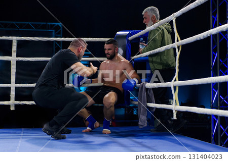 Cornered boxer receives strategic advice from trainer during intense bout. Cornered boxer receives strategic advice from trainer during intense bout. 131404023