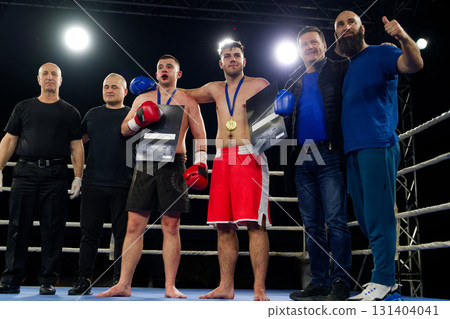 A boxer celebrates victory with his team in an emotional embrace after a grueling match. 131404041