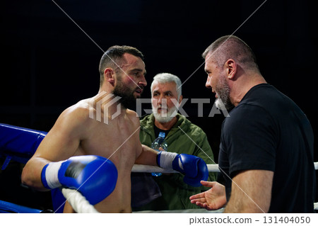 Cornered boxer receives strategic advice from trainer during intense bout. Cornered boxer receives strategic advice from trainer during intense bout. 131404050