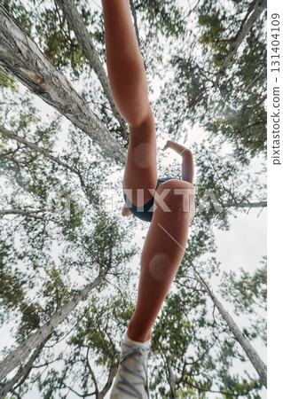 Adventurous Woman Overcoming Forest Obstacles with Determination and Agility. Adventurous Woman Overcoming Forest Obstacles with Determination and Agility. 131404109