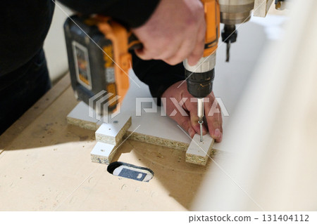 Close-Up of Worker Drilling Wooden Boards to Prepare for Further Processing 131404112