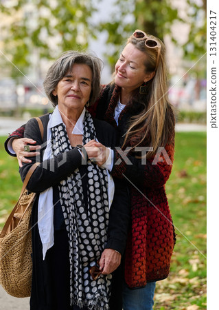 A Heartfelt Embrace: A Daughters Support for Her Mother on a Beautiful Autumn Day. 131404217