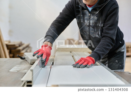 Close Up of Worker Carefully Cutting and Planing Wooden Pieces for Furniture in Wood Industry Close Up of Worker Carefully Cutting and Planing Wooden Pieces for Furniture in Wood Industry 131404308