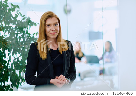 Portrait of a Blonde Businesswoman in a Modern Office with Her Workspace and Colleagues in the Background. 131404400