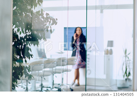 Businesswoman Talking on Smartphone in Modern Office Setting. 131404505