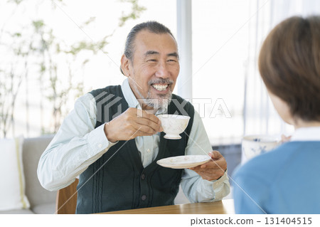 Senior men and women drinking tea facing each other 131404515