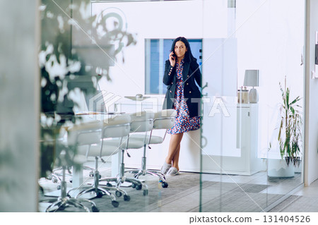 Businesswoman Talking on Smartphone in Modern Office Setting. 131404526