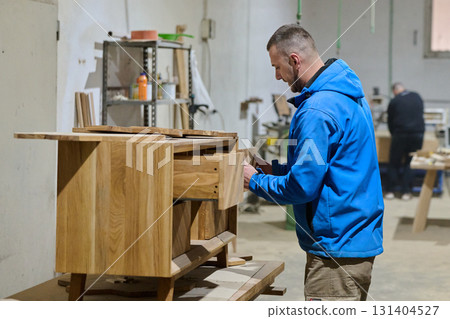 Close Up of Worker Carefully Cutting and Planing Wooden Pieces for Furniture in Wood Industry 131404527
