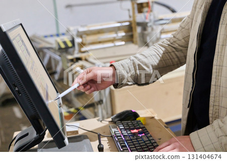 Operator Entering Coordinates on Computer for CNC Machine to Precisely Cut Wooden Pieces Operator Entering Coordinates on Computer for CNC Machine to Precisely Cut Wooden Pieces 131404674