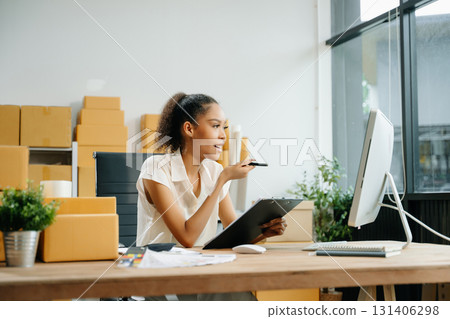 Young business owner woman prepare parcel box and standing check online orders for deliver 131406298