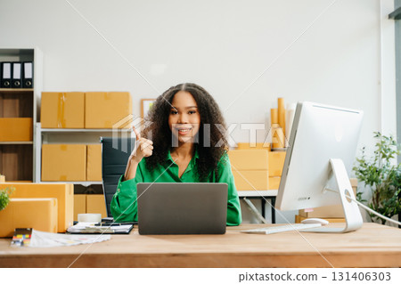 Young business owner woman prepare parcel box and standing check online orders for deliver 131406303