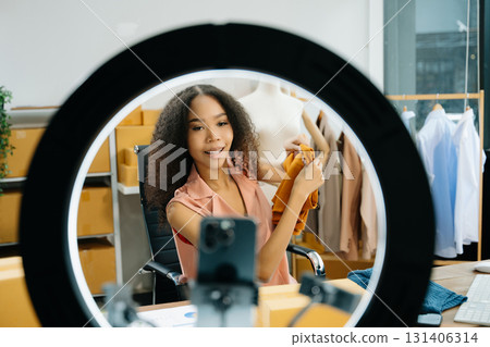 Young influencer showcasing clothing in a creative workspace, highlighting ecommerce, digital marketing Young influencer showcasing clothing in a creative workspace, highlighting ecommerce, digital marketing 131406314