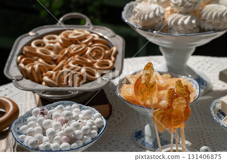 Traditional Russian sweets including rooster lollipops, baranki, zephyr, and candied fruits served in vintage porcelain and silverware under sunlight Traditional Russian sweets including rooster lollipops, baranki, zephyr, and candied fruits served in vintage porcelain and silverware under sunlight 131406875