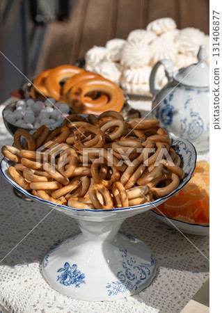Traditional Russian tea setting with a porcelain bowl full of sushki (dry bread rings), marmalade, marshmallows, and a blue-and-white teapot 131406877