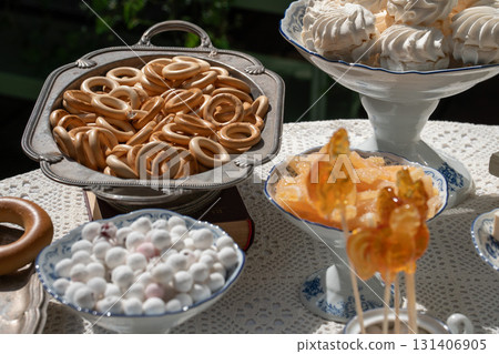 Traditional Russian sweets including rooster lollipops, baranki, zephyr, and candied fruits served in vintage porcelain and silverware under sunlight Traditional Russian sweets including rooster lollipops, baranki, zephyr, and candied fruits served in vintage porcelain and silverware under sunlight 131406905