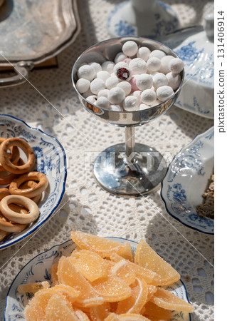 Vintage-style tea table with dried fruits, traditional Russian baranki, and powdered berries served in elegant porcelain and metalware 131406914