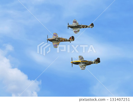 Supermarine Spitfire, Hawker Hurricane and P-51D Mustang Air Force fighter aircraftsflying on a blue sky Supermarine Spitfire, Hawker Hurricane and P-51D Mustang Air Force fighter aircraftsflying on a blue sky 131407251