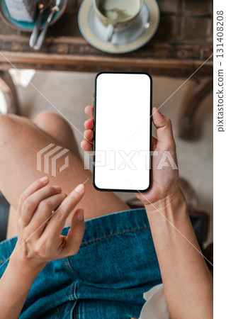 Close-up of a woman holding a smartphone with a blank screen, perfect for app mockups or design presentations. 131408208
