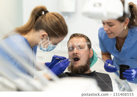 Two female dentists treat man teeth at dental clinic 131408555