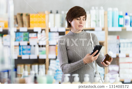 Female customer checking syrup medicine details on smartphone 131408572