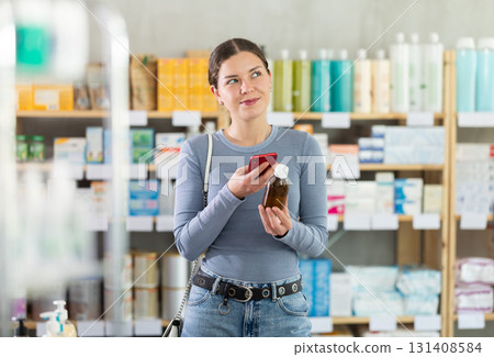 Young girl customer scanning barcode on syrup in drugstore 131408584