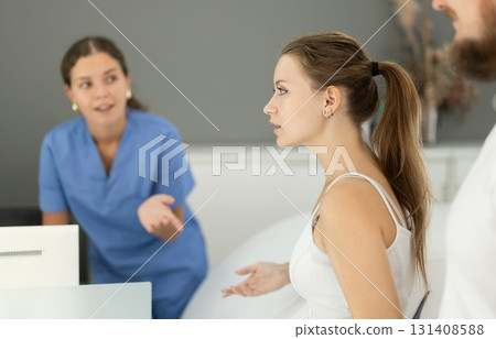 Woman stands near the reception of the dentistry and communicates with the administrator 131408588