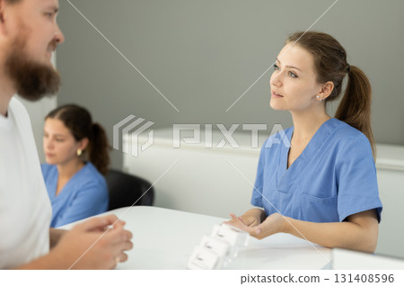 man is standing near the reception in the dentistry and asks about an appointment with a dentist man is standing near the reception in the dentistry and asks about an appointment with a dentist 131408596
