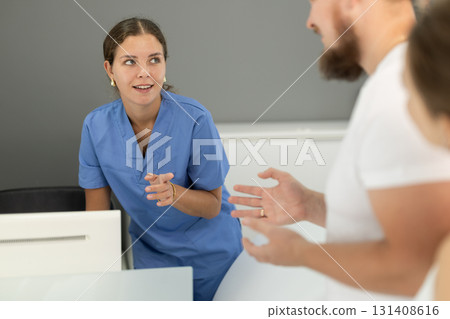 Man stands near the reception and asks questions to the administrator in the dentistry Man stands near the reception and asks questions to the administrator in the dentistry 131408616