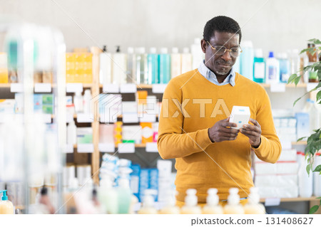 Man in glasses attentively carefully selects pills in modern pharmacy 131408627