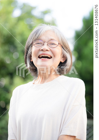 Elderly grey-haired woman smiling against a green background, close-up 131408676