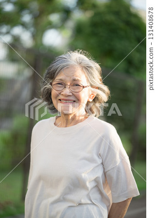 Elderly grey-haired woman smiling against a green background, close-up 131408678