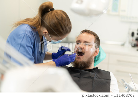 Female dentist treat man teeth at dental clinic Female dentist treat man teeth at dental clinic 131408702