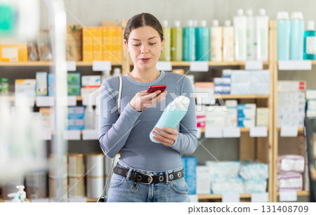Young girl scanning QR code on bottle on shampoo in store 131408709